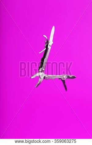 Multitool Is A Multi-functional Tool On A Pink Background. The Concept Of An Open, Flying Multi-tool