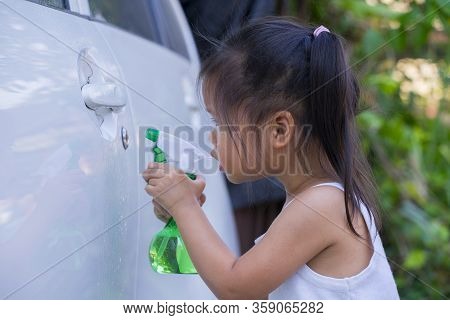 Asian Children Spry Soap To Clean Car Door Handle.
