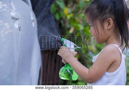 Asian Children Spry Soap To Clean Car Door Handle.