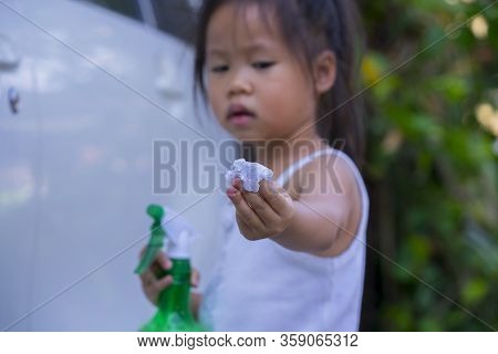 Asian Children Spry Soap To Clean Car Door Handle.