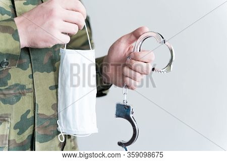 Police Officer With Face Mask And Handcuffs In Khaki Colored Uniform Stops, Arrest Criminal On The S