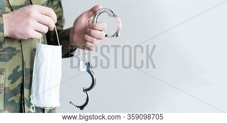 Police Officer With Face Mask And Handcuffs In Khaki Colored Uniform Stops, Arrest Criminal On The S
