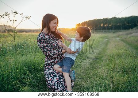 Stilish Mother And Handsome Son Having Fun On The Nature. Happy Family Concept. Beauty Nature Scene