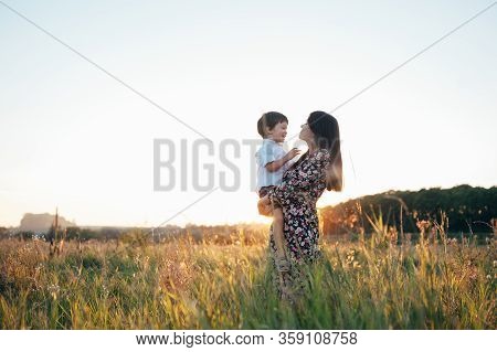 Stilish Mother And Handsome Son Having Fun On The Nature. Happy Family Concept. Beauty Nature Scene
