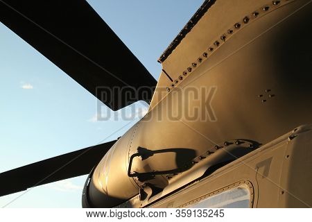 Bottom View Of A Olive Drab Military Helicopter With Propeller Blades Against A Blue Sky