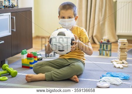 Soccer Ball In A Medical Mask. Activities At Home With Your Children During Home Coronavirus Quarant