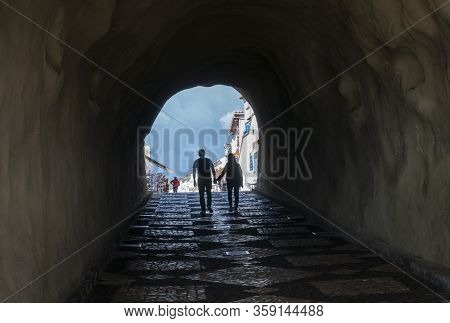Albufeira, Algarve, Portugal, February 2020 - Silhouette Of A Couple Walking Through A Pedestrian Tu