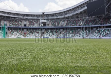 Interior View Of Green Grass Field And Empty Seating Stadium Grandstands Under Summer Clouded Blue S