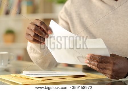 Close Up Of Black Man Hands Putting A Letter Inside An Envelope On A Desk At Home