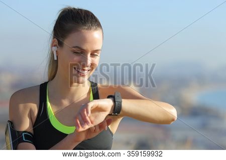 Happy Runner Wearing Wireless Earbuds Checking Smart Watch After Sport