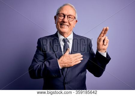 Grey haired senior business man wearing glasses and elegant suit and tie over purple background smiling swearing with hand on chest and fingers up, making a loyalty promise oath