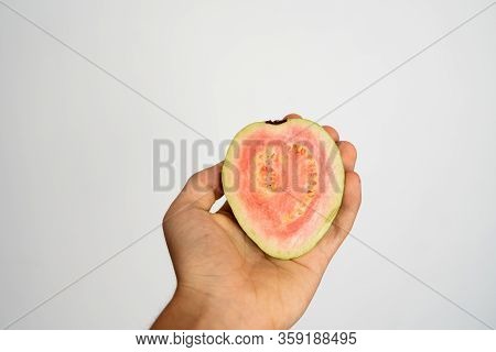 Female Hand Holding A Half Of Ripe Guava On A White Background.