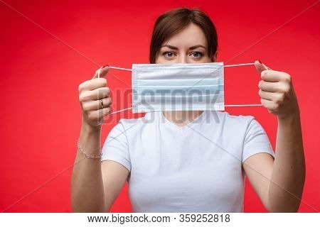 Woman With Aseptic Mask In Hands. Isolate On Red.
