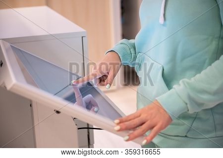 Faceless Woman Touching The Screen Of A Self-service Device In A Store. Device Store Navigator. Self
