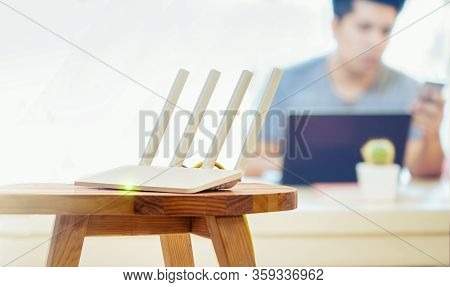 Closeup Of A Wireless Router And A Man Using Smartphone On Living Room At Home Ofiice, Equipment For