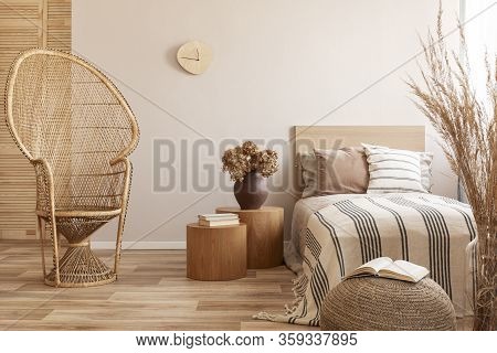 Peacock Chair Next To Single Bed With Beige Bedding And Warm Blanket, Real Photo