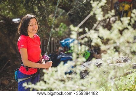 A Woman Is Belaying A Partner, Rock Climbing Safety, Trust In The Partner, Equipment For Belaying In