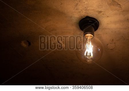 An Electric Lamp Shines On A Brown Background On The Ceiling.