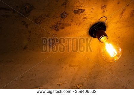 Vintage Burning Light Bulb On A Brown Background On The Right.