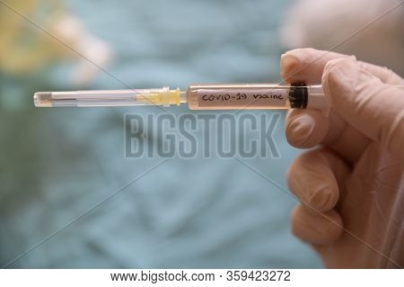 Close Up Shot Of A Syringe With The Word Coronavirus Vaccine.he Is Holding Her Hand With A White Lat