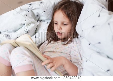 Profile Of Hard Working Curious Smart Girl Learning To Read, Looking At Text Attentively, Reading In
