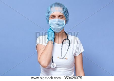 Horizontal Shot Of Young Woman Wearing Disposable Hat, Rubber Gloves, Medical Protective Mask, Havin