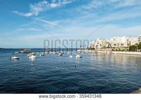 The Cityscape Of Bugibba City In Malta With A View At The Sea, Port, Palms, Apartments And The Dawre