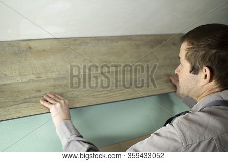 A Worker Puts A New Laminate On The Floor. Laying The Floor Covering. Master In The House.