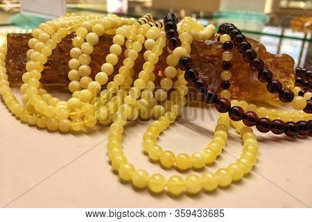 A Lot Of Baltic Amber White Beads Lie On A Large Piece Of Natural Amber. Template For Decorating A J