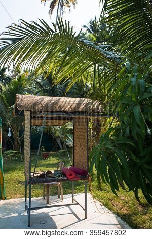 Wicker Gazebo Among Tropical Palms With Yoga Mats. A Place For Outdoor Yoga In India, Kerala.