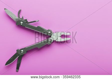 Multitool Is A Multi-functional Tool On A Pink Background. The Concept Of An Open, Flying Multi-tool