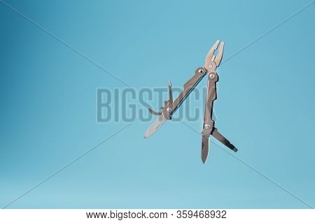 The Multitool Multi-function Tool Hovers On A Blue Background. The Concept Of An Expanded Multi-tool