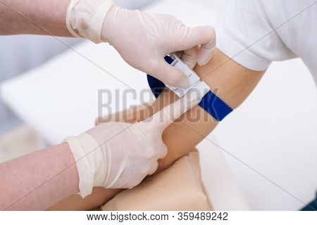 Laboratory Assistant Preparing Patient To Do A Blood Analysis. Nurse Tightening The Medical Tourniqu