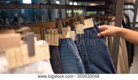 Female Hand Choosing Modern Fashion Women Clothes Hang On Stanless Steel Hangers Rack At Clothing St