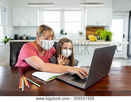 Coronavirus School Closures And Lockdown. Mum And Bored Daughter With Masks Studying Online At Home
