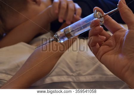 The Boy Is Afraid Of Injections. The Pediatrician With A Syringe. Baby Medical Syringe. Compulsory T