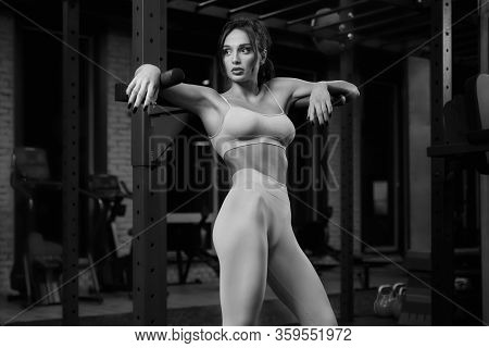 Monochrome Portrait Of Brunette Fit Girl In Light Sportswear Posing Near Parallel Bars. Srtong Woman