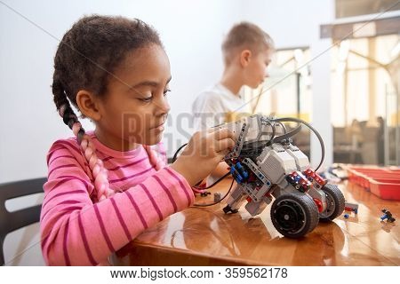 Building Kit With Colorful Pieces For Group Of Multiracial Kids Creating Toys. Close Up Of Concentra