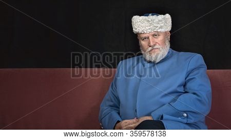 Elderly Man With A Gray Beard In A Hat And A Blue Caftan. Cossack Costume