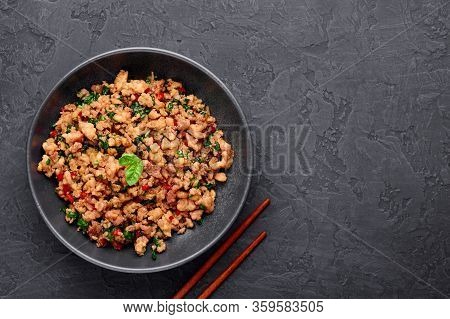 Pad Krapow Gai - Thai Basil Chicken In Black Bowl At Dark Slate Background. Pad Krapow Is Thai Cuisi