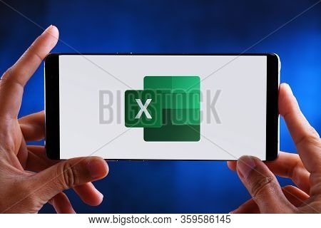 Poznan, Pol - Feb 19, 2020: Hands Holding Smartphone Displaying Logo Of Microsoft Excel, A Spreadshe