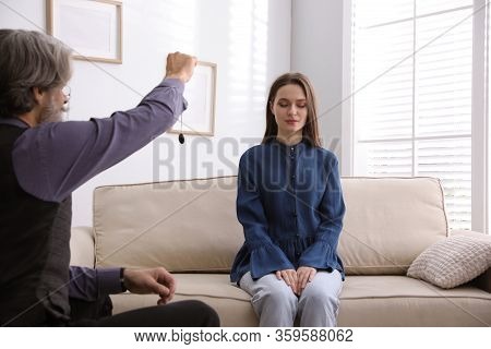 Psychotherapist Using Pendulum During Hypnotherapy   Session In Office