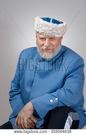 Elderly Man With A Gray Beard In A Hat And A Blue Caftan. Cossack Costume