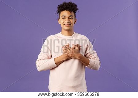 Portrait Of Romantic Handsome Hispanic Man With Dreads, Hold Hands Pressed To Heart And Smiling Plea