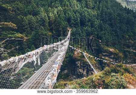 Suspension Bridge Decorated With Multicolored Tibetan Prayer Flags Hinged Over Gorge. Everest Base C