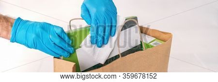 Coronavirus wiping down grocery packages after receiving home delivery wearing gloves, using disinfecting sanitizing wipes to wipe the surfaces clean. Cleaning of COVID-19 virus.