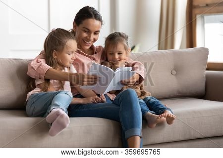 Happy Young Mixed Race Babysitter Reading Book To Children.