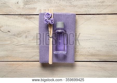 Spa Composition Of A Bottle Of Oil, Wooden Incense Sticks With Roses And A Purple Napkin On A Wooden
