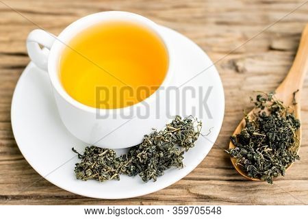 Dry Gynostemma Pentaphyllum Leaf With Brewed Tea In A White Cup On The Wood Floor