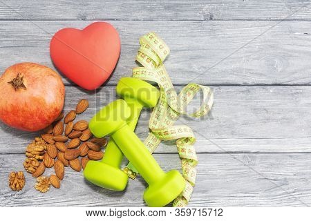 Pomegranate Fruit, Dumbbells, Measuring Tape On The Background Of A Wooden Texture. Fitness, Sports 